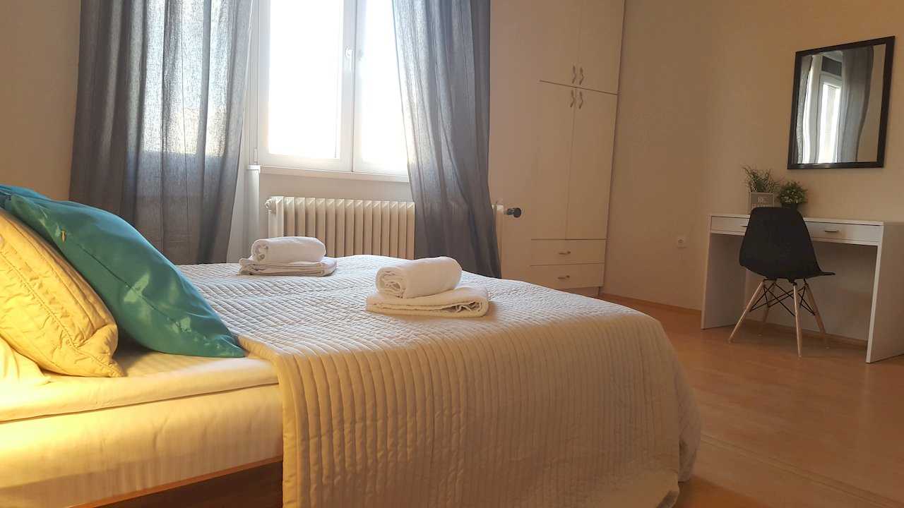 Bedroom with bed, built-in white wardrobe, white desk with mirror, and modern black chair – Apartment Opera – City Break Apartments