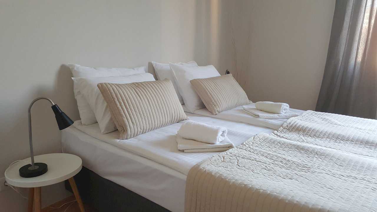 Bedroom with double bed, beige accent pillows, rolled white towels, and round bedside table with lamp – Apartment Opera – City Break Apartments