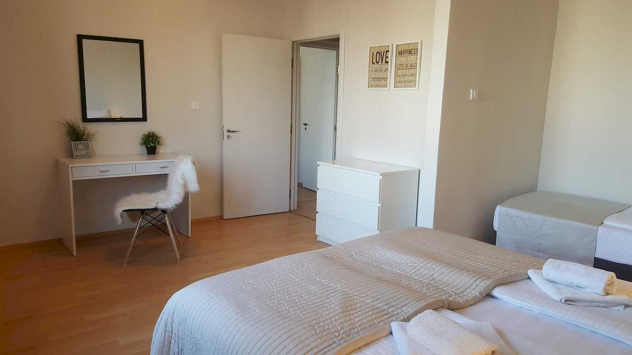 Sleeping area with multiple beds, white desk with plants, faux-fur-covered chair, dresser, and motivational posters – Apartment Opera – City Break Apartments