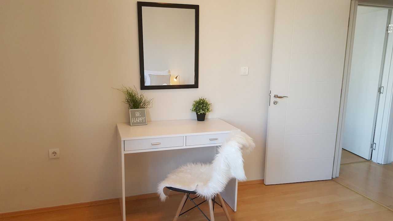 Desk nook with BE HAPPY decor, faux-fur-covered chair, potted plants, and black-framed mirror – Apartment Opera – City Break Apartments