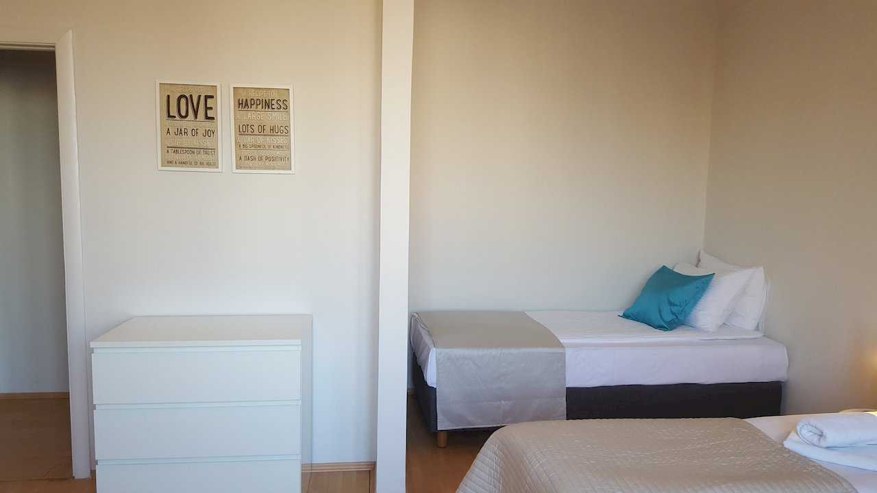 Corner with two beds, white dresser, and LOVE and HAPPINESS typography posters above it – Apartment Opera – City Break Apartments