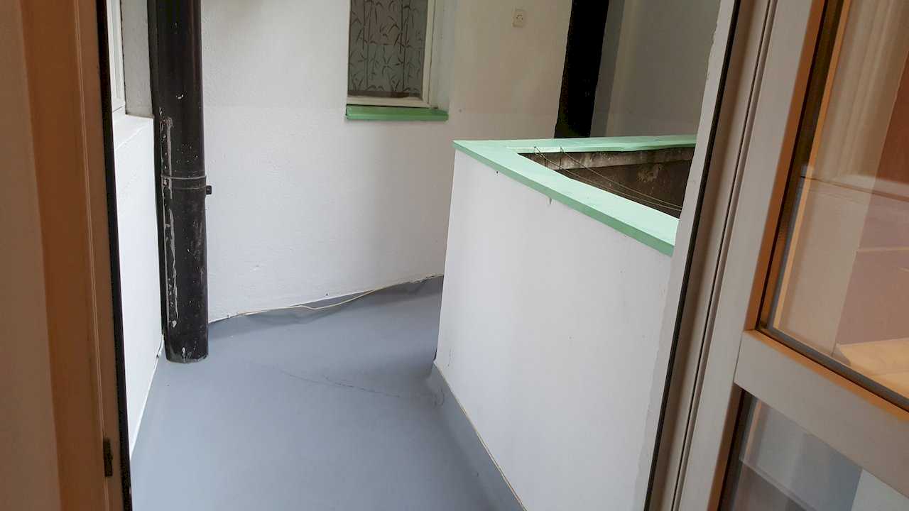 Small balcony with grey floor, white walls, low parapet, and mint-green window ledge – Apartment Opera – City Break Apartments