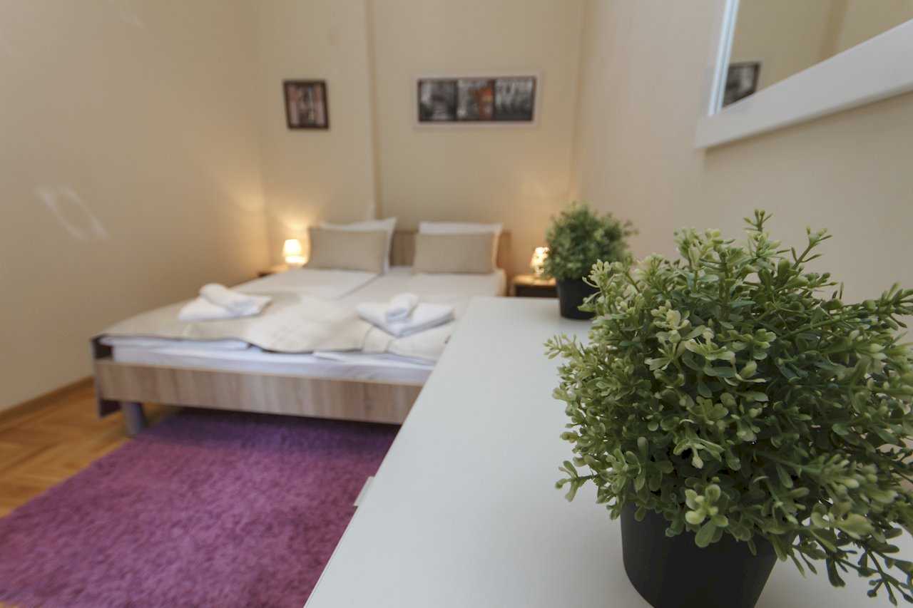 Apartment Parlament 2 (Vlajkovićeva Street, Belgrade) – bedroom with double bed, purple rug and plants on the dresser