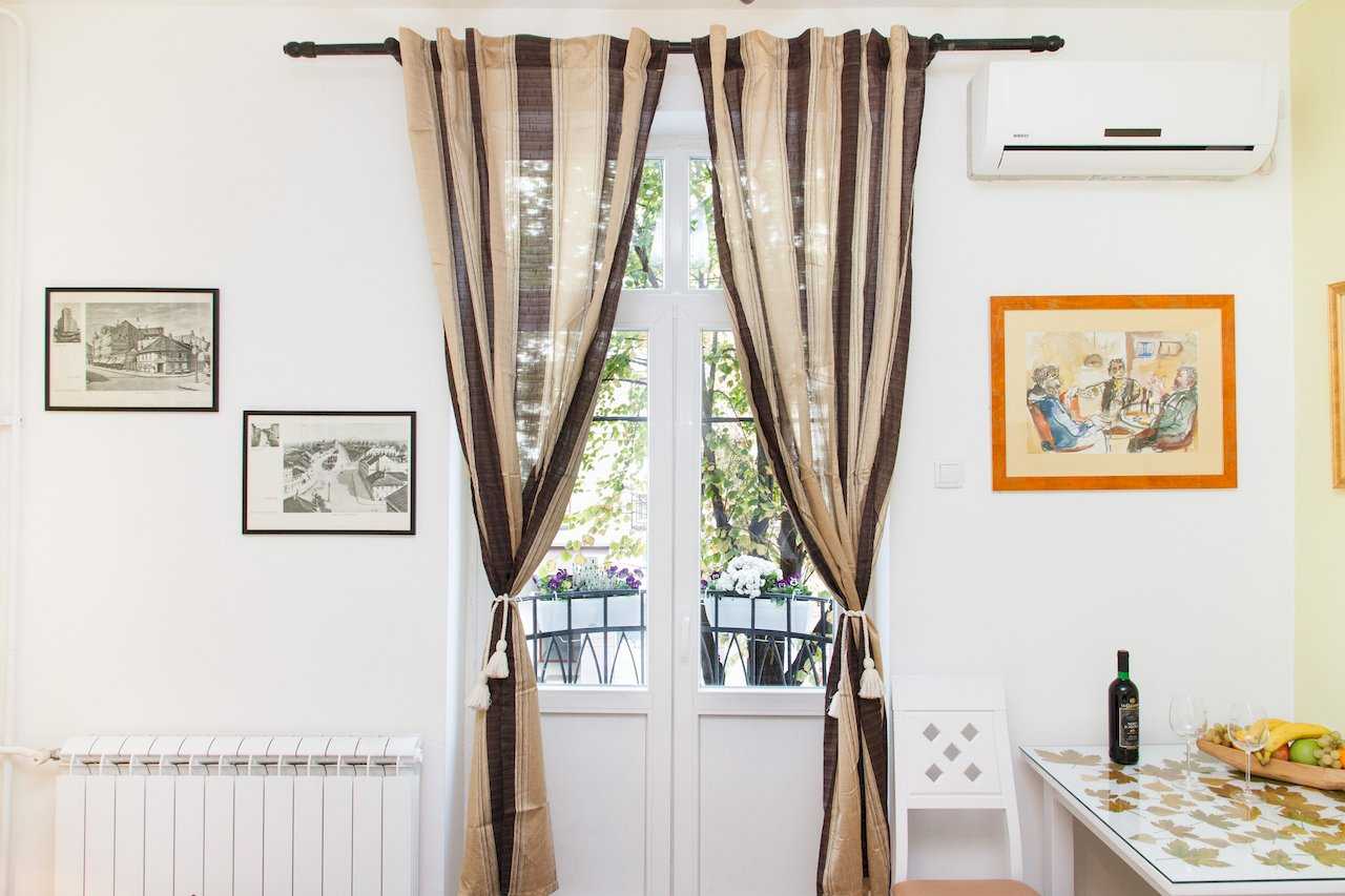 Apartman Sweet (Beograd, centar) – prozor sa prugastim zavesama, grafike na zidu i deo trpezarije