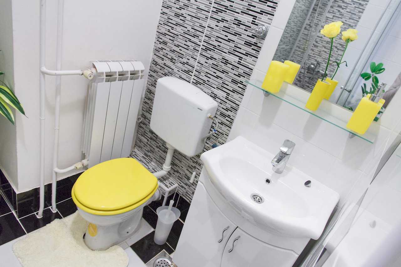 Apartman Sweet (Beograd, centar) – kupatilo sa WC šoljom, lavaboom i žutim aksesoarima uz mozaik zid