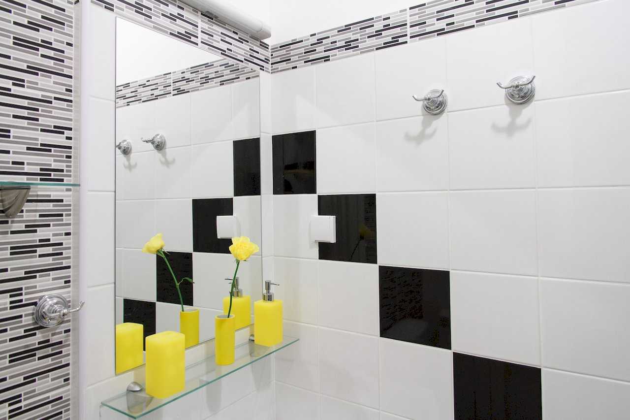 Apartman Sweet (Beograd, centar) – lavabo sa ogledalom, belo-crne pločice i žuti aksesoari na staklenoj polici