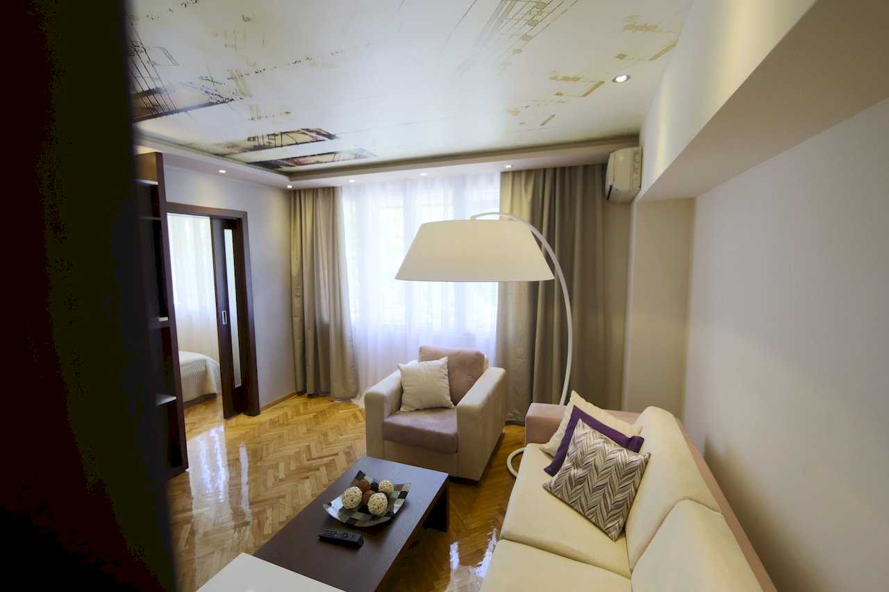 Apartment Taš 2 (King Alexander Boulevard, Tašmajdan, Belgrade) – living area with sofa, armchair, arched floor lamp and view toward the bedroom