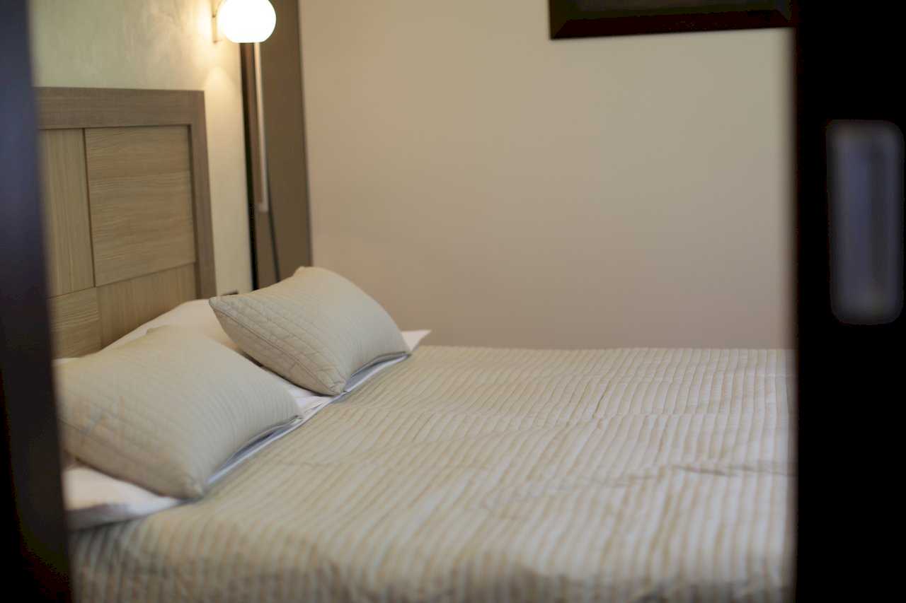 Apartment Taš 2 (King Alexander Boulevard, Tašmajdan, Belgrade) – detail of double bed with wooden headboard and spherical wall lamp