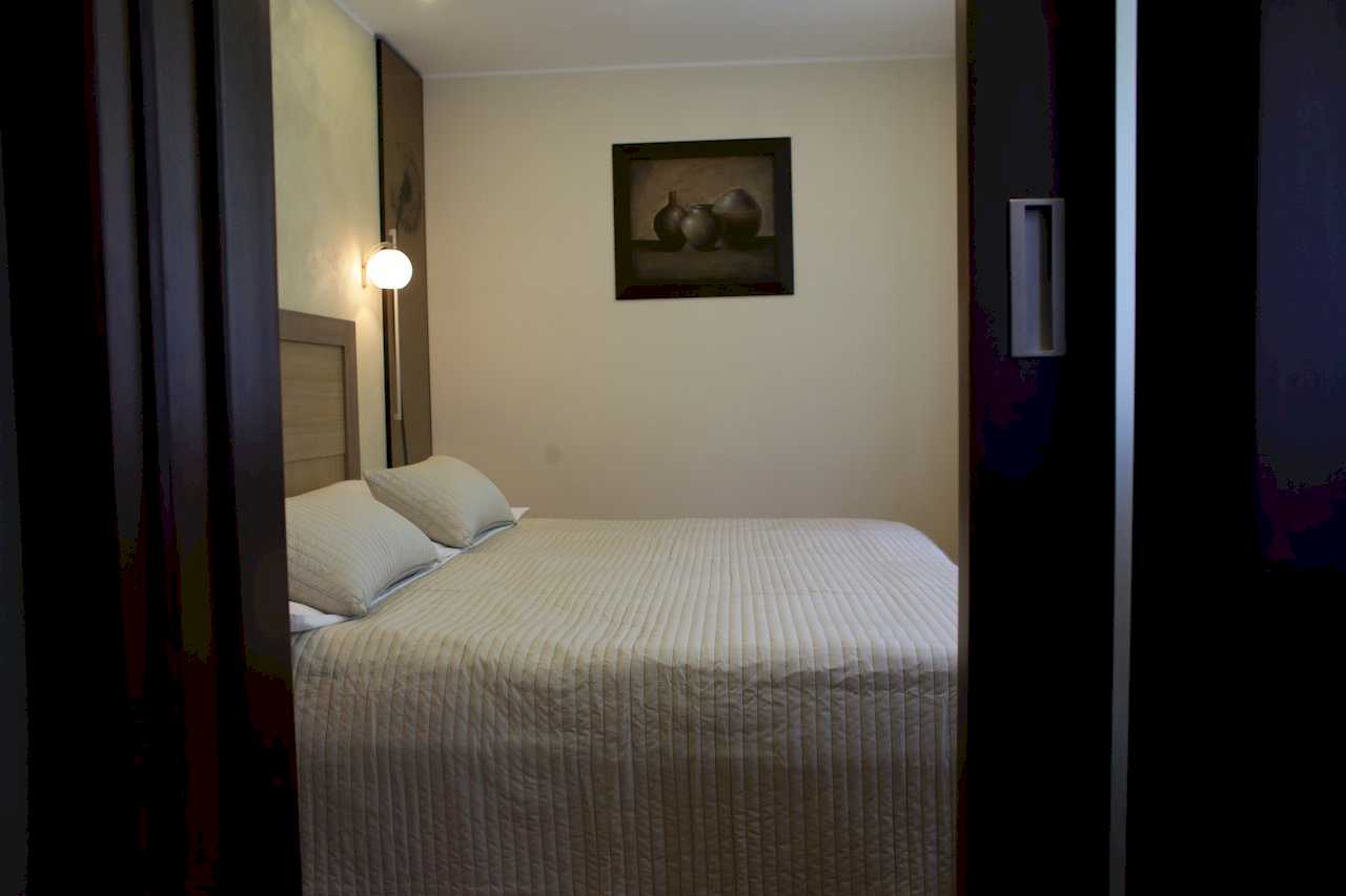 Apartment Taš 2 (King Alexander Boulevard, Tašmajdan, Belgrade) – view through doorway into bedroom with double bed and artwork above the bed