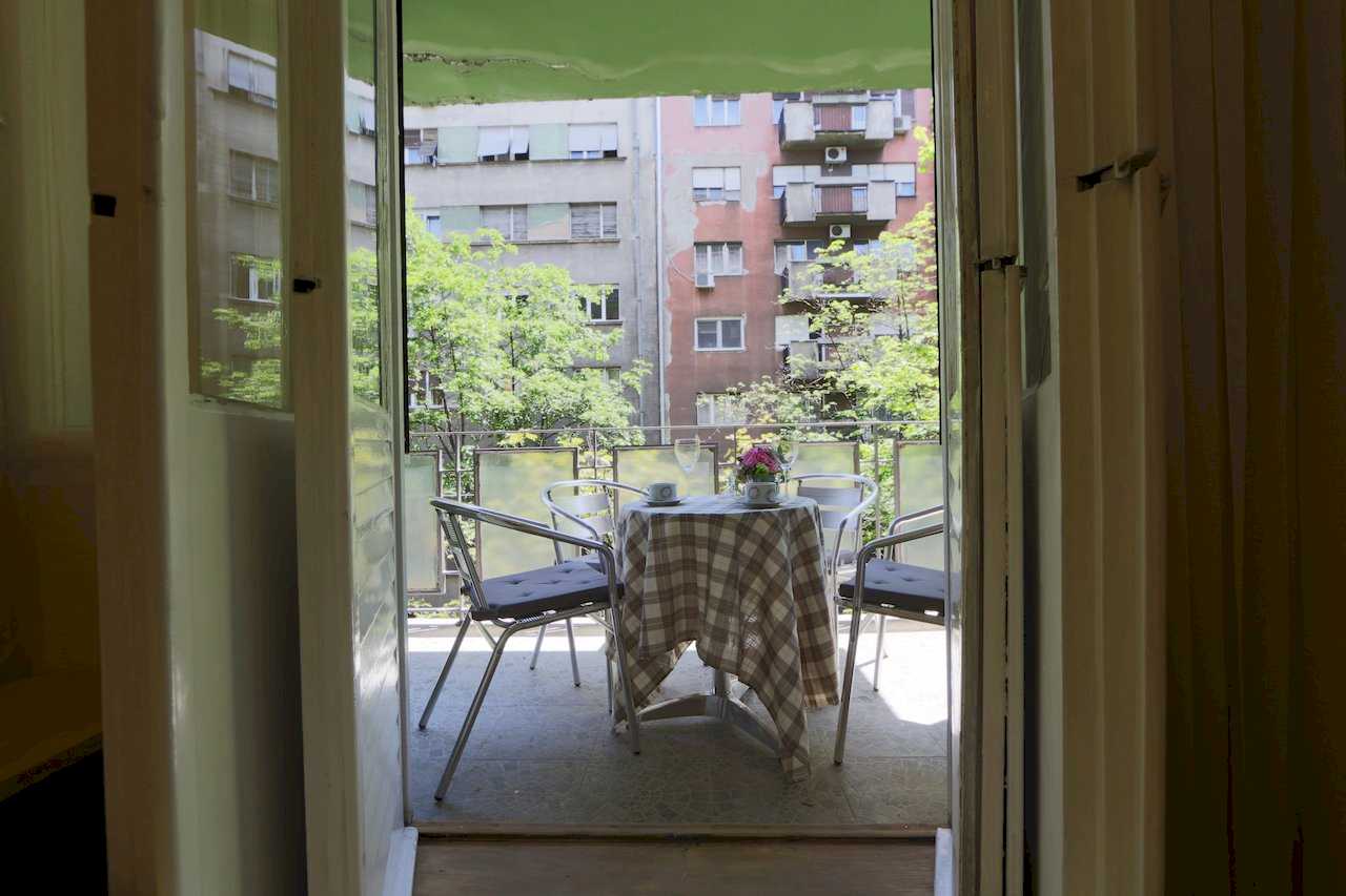 Apartment Taš 2 (King Alexander Boulevard, Tašmajdan, Belgrade) – terrace with round table, metal chairs and view of buildings and trees