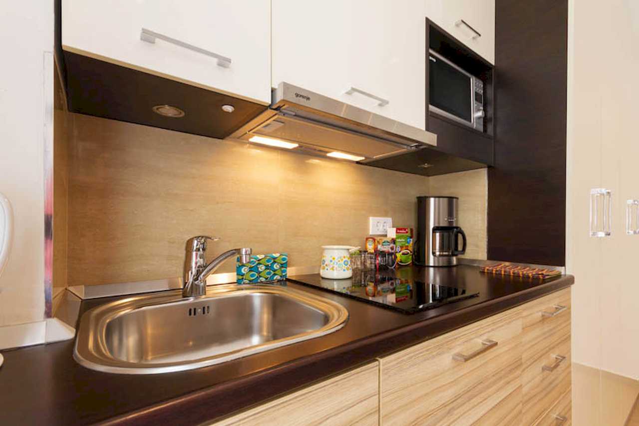 Kitchen worktop with sink, glass-ceramic hob, built-in extractor, microwave in open shelving and coffee maker – Apartment Trg 1 – City Break Apartments