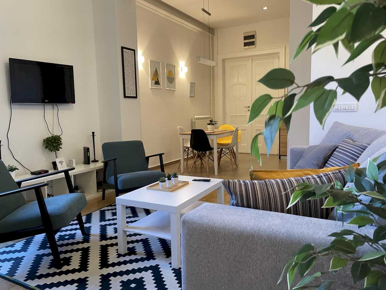 Širok pogled na dnevnu sobu i trpezariju sa šarenim stolicama – Apartman Trg 2 – City Break Apartments