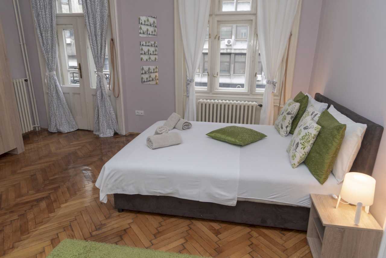 Četvorosobni stan Trg 4 (Kolarčeva, Beograd) – spavaća soba sa bračnim krevetom, zelenim detaljima i balkonskim vratima
