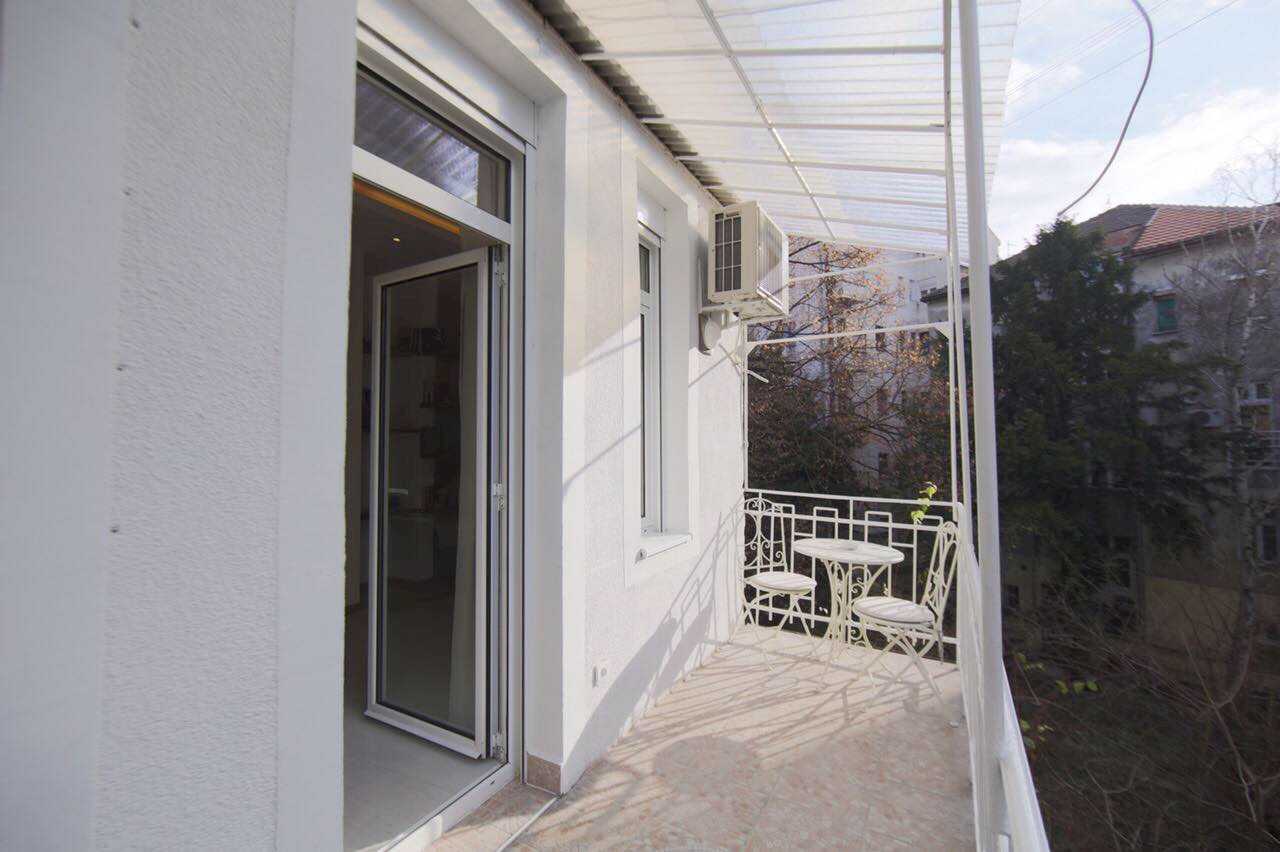 Apartman Twin 1 (Carice Milice, centar Beograda) – terasa sa belim metalnim stolom i dve stolice, providna nadstrešnica i pogled na susedne zgrade