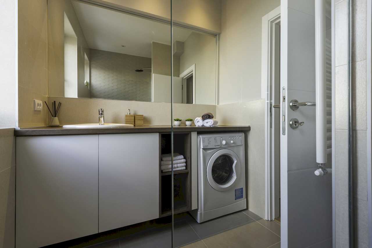 Bathroom with sink, large mirror and washing machine – Apartment Urban Zen – City Break Apartments