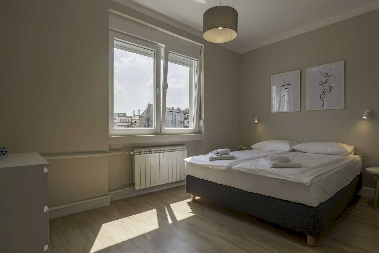 Bedroom with double bed and city view through windows – Apartment Urban Zen – City Break Apartments