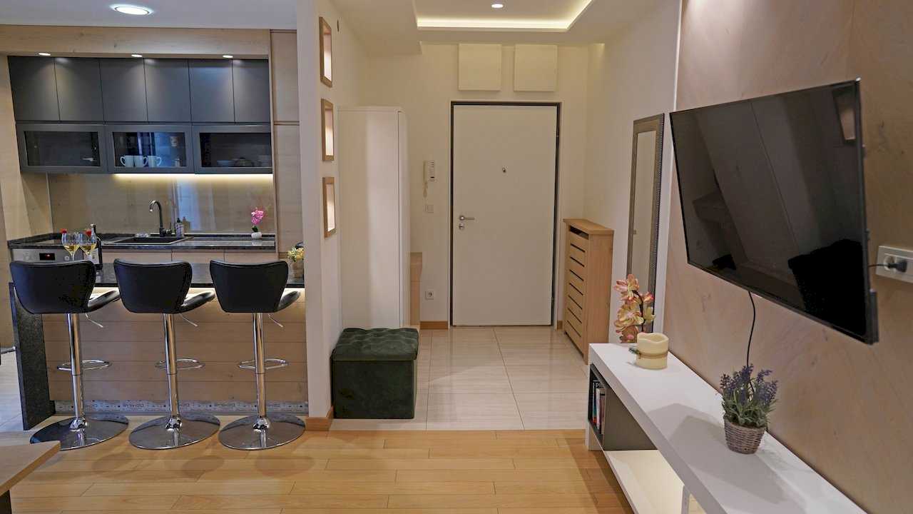 Apartment Vuk (Vuk's Monument, Belgrade) – kitchen with bar, entryway and part of living room with TV